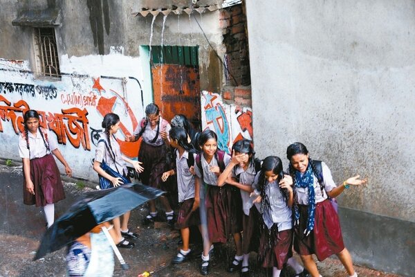 陣雨過後，加爾各答一群女學生一日爭相淋著屋頂流下的雨水。 （歐新社）