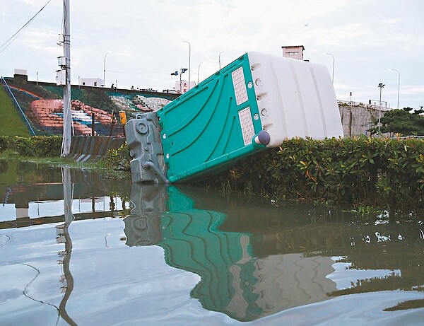 因昨日午暴雨影響,二重疏洪道部分地區淹水,水退後堤外停車場的流動廁所移位,傾倒在樹叢上。 記者曾原信/攝影