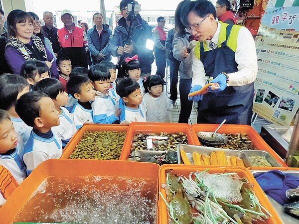 彰化市長林世賢(右)扮起菜市場達人,帶領幼兒園小朋友逛華陽市場,還穿起圍裙戴上手套,現場解說如何挑選新鮮海鮮食材。(謝瓊雲攝)