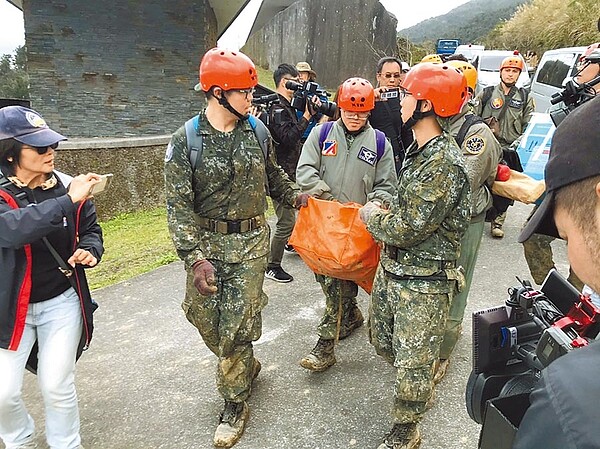 黑鷹直升機墜毀山區，搜索人員3日提著尋獲的黑盒子下山。（胡健森攝）