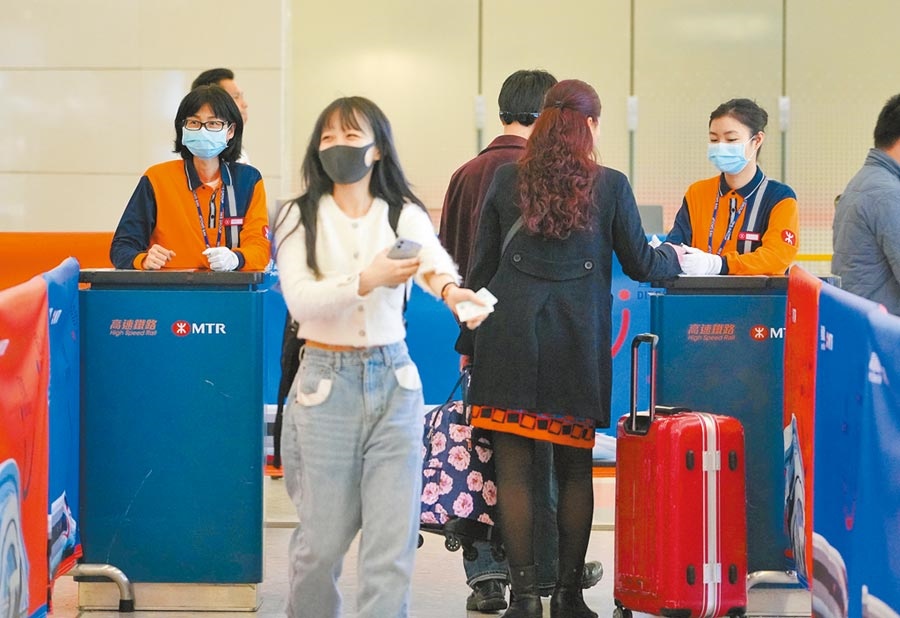 面對不明病毒性肺炎，香港公布應變計畫，4日高鐵香港西九龍站的檢票員戴上口罩，核查旅客身分。圖／中新社