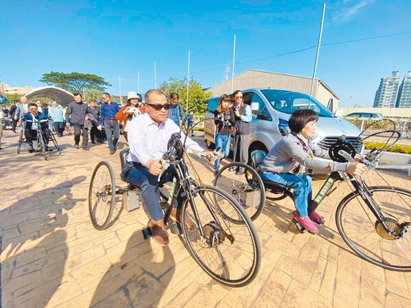 高市觀光局9日推出3條無障礙遊程，副市長葉匡時（左）試乘提供輪椅族使用的手搖車。（高市觀光局提供）