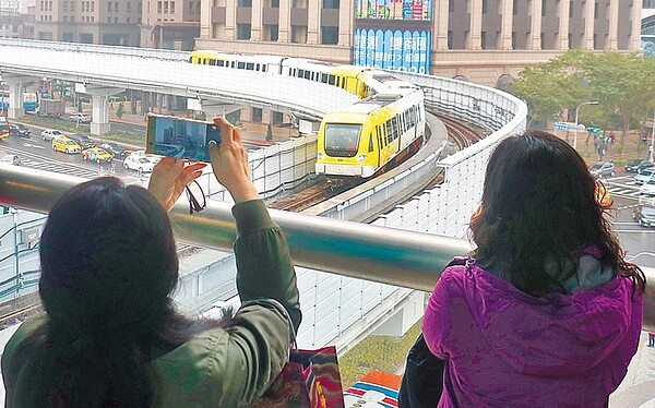 新北捷運環狀線試乘,民眾看見黃白相間的列車,拿起手機猛拍。(實習攝影記者林益民攝)