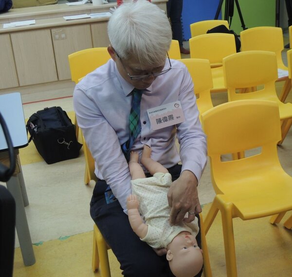 馬偕醫院小兒科陳偉燾醫師示範嬰幼兒誤食發生呼吸困難時的急救措施。圖／靖娟基金會提供