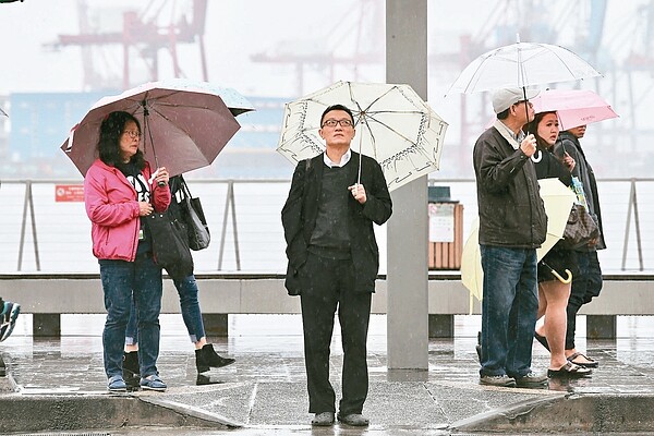 昨天氣轉為濕冷，來往民眾人手一支雨傘。 記者許正宏／攝影