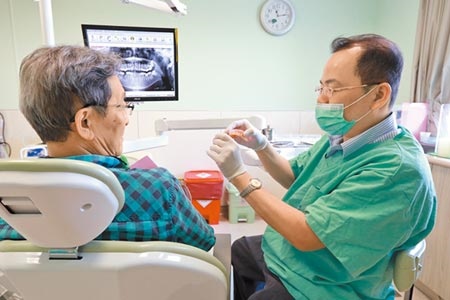 亞大醫院牙科主任廖明德（右）向患者（非當事人）解釋「吸附性全口活動假牙」的治療方式。（林欣儀攝）