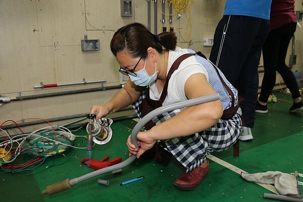 學員拿起噴火槍燒烤PVC做彎管。圖／新北社會局提供