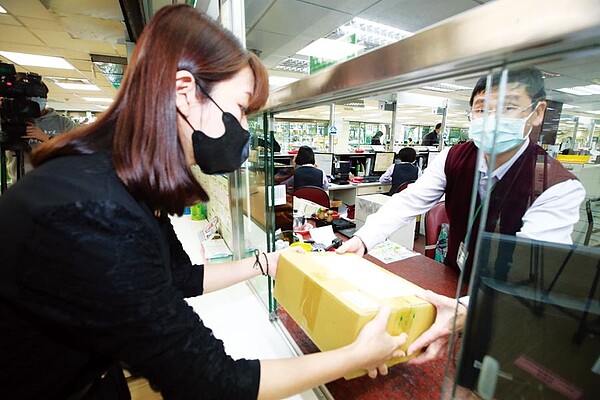台灣民眾從9日起口罩將開放申請,寄送居住海外配偶或二等親。民眾可透過網路或親自向國貿局申請,取得許可證號碼後交給郵局人員換取郵局提供的條碼貼在包裝箱上,即可通過海關寄給親友。圖為民眾到郵局寄送口罩給海外親友。(本報資料照片)