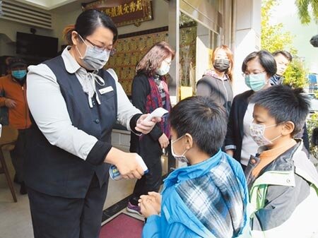 彰化縣的學童們在老師教導下,噴酒精消毒手部、並以額溫槍量測體溫。(謝瓊雲攝)