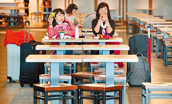 新冠肺炎嚴重影響航空業及旅遊業,桃園機場12日出入境人數跌至6萬多人,約為平日的5成,在二航廈的美食街內,只有旅客三三兩兩地在用餐。(范揚光攝)