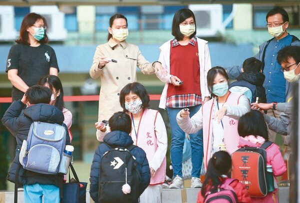 因應新冠肺炎疫情，學生進校必須量體溫，老師戴著口罩人手一支額溫槍，成為前所未見的開學景象。（圖／本報資料照片）