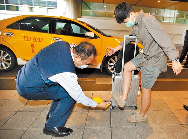 交通部宣布,桃園機場防疫車隊4日起上路,以減少防疫漏洞,1名3日抵達桃園機場的旅客,在搭乘計程車前,雙手、行李及鞋底接受消毒。(范揚光攝)