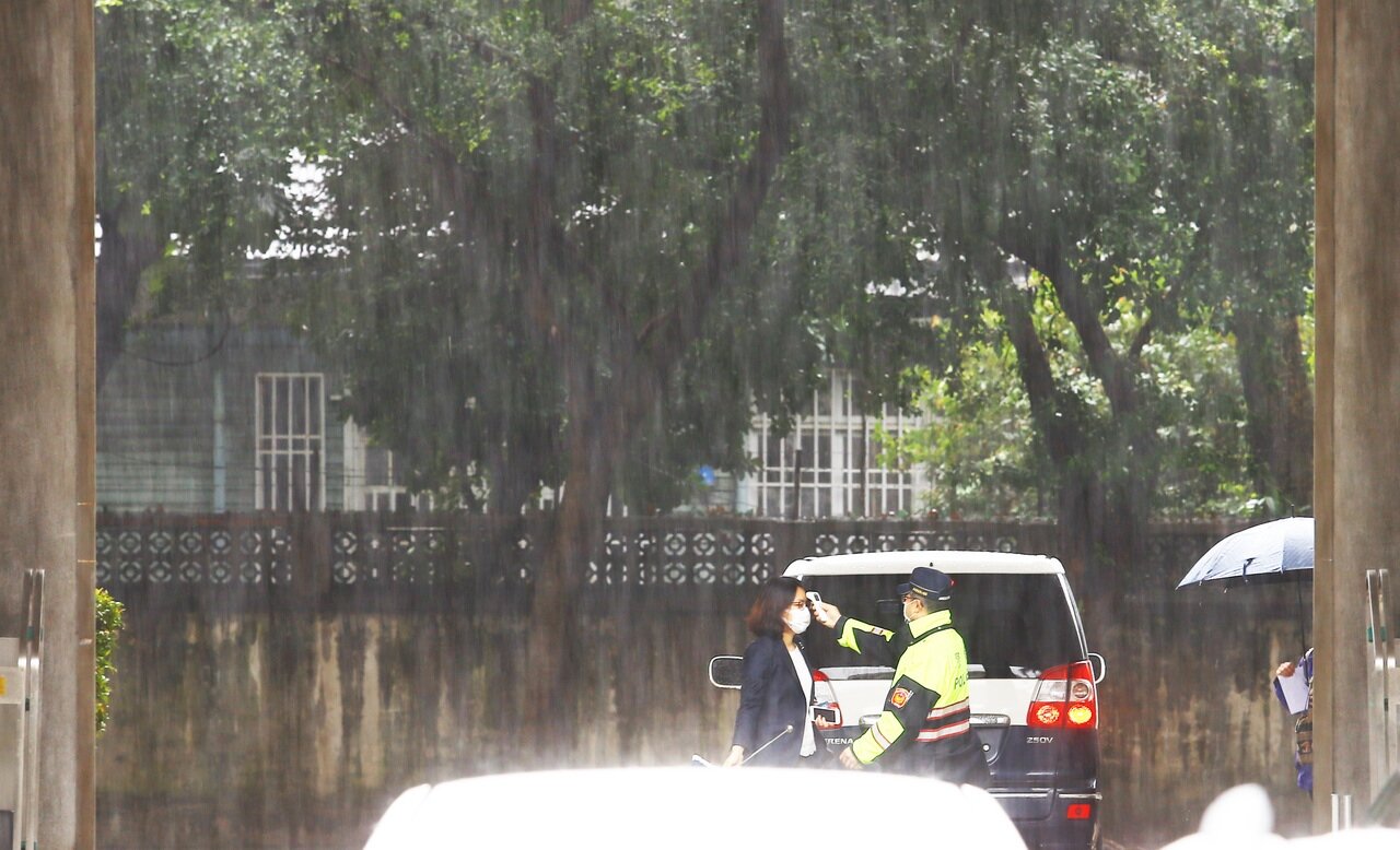 鋒面通過，氣象局針對北台灣6縣市發出大雨特報，經濟部大門警衛在傾盆大雨中為一位進入經濟部洽公的民眾量測額溫。記者杜建重／攝影