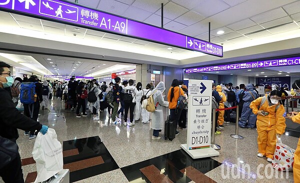 中央流行疫情指揮中心將從24日起禁止旅客來台轉機,桃園國際機場凌晨尖峰時段有許多轉機旅客,不少人穿著防護衣搭機。 記者鄭超文/攝影