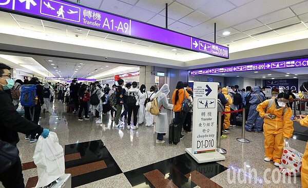 中央流行疫情指揮中心將從24日起禁止旅客來台轉機，桃園國際機場凌晨尖峰時段有許多轉機旅客，不少人穿著防護衣搭機。 記者鄭超文／攝影