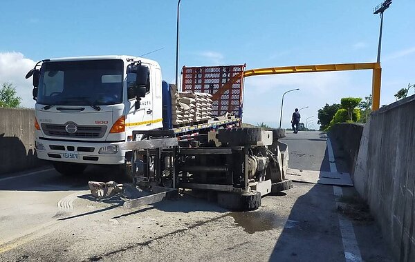 一輛拖板車載著水泥及堆高機,堆高機勾斷3.5米的限高鋼架,摔在路面上。圖/羅㬩鎂提供