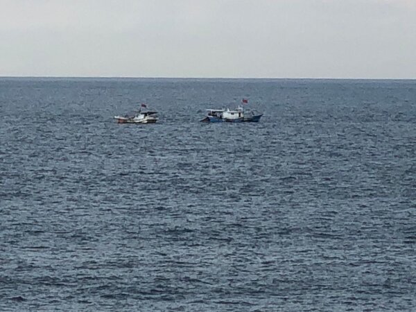 北臺灣唯一的飛魚追逐網船隊，船頂立著國旗，時而分開，時而靠近。圖／新北市政府漁業及漁港事業管理處提供