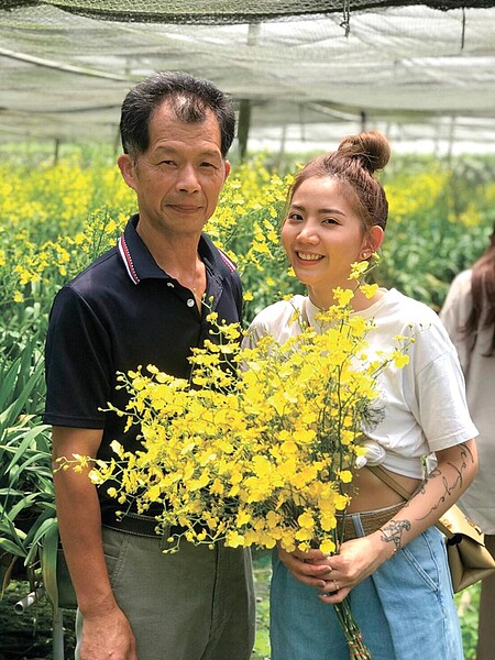 臺中市政府農業局為推動花卉紓困,與網紅陳艾琳合作,以臺中在地花卉提供一些實用插花知識宣傳影片行銷推廣;圖為文心蘭業者羅忠勇(左)與陳艾琳(右)合影。圖/農業局提供