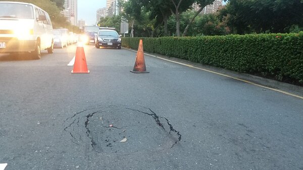 高雄市鬧區道路23日傍晚突然凹陷,警方派員封路,避免路面凹陷處繼續擴大。圖/記者林保光攝影