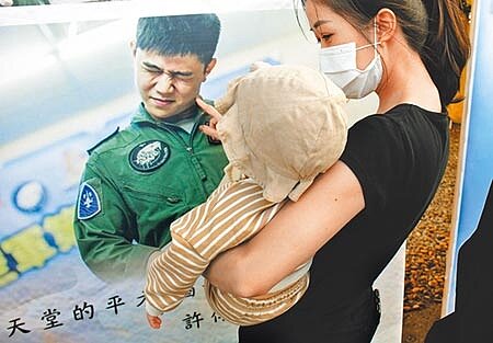 殉職飛官朱冠甍的滿周歲女兒，由親人抱著，凝視著已經在天上的爸爸遺容，令人鼻酸。（莊哲權攝） 