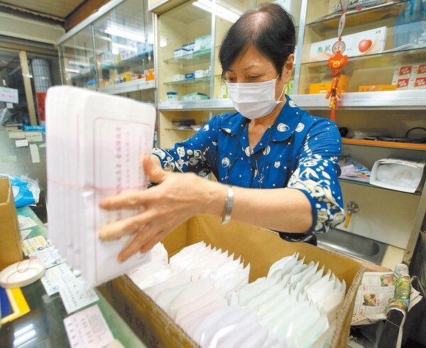 台灣本土疫情蠢動，口罩搶購潮再現，政府傳將擴大徵收口罩至總產量8成，必要時不排除全數徵用。圖為藥局人員整理口罩。（陳怡誠攝）
