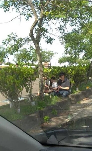 涉嫌肇事蘇姓駕駛的兒子,車禍發生後坐在分隔島上滑手機,被拍下上傳網路。 記者卜敏正/翻攝