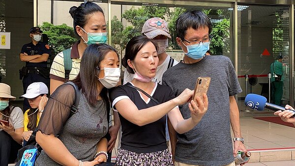 一群小明父母今日下午前往疾管署陳情,聽聞小明返台政策鬆綁,看著手機上顯示的新聞確認這項消息。記者呂佳蓉/攝影