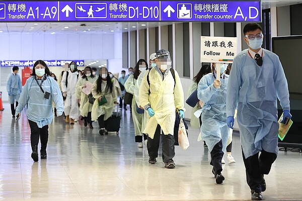 在防疫人員引導下,一百一十四名從英國入境桃機、戴口罩、穿隔離衣的旅客,緩步走至防疫專區(A七內候機室),並未與其他旅客混流。記者鄭超文/攝影