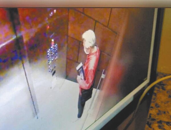 黃芳彥住處電梯監視器,拍下他最後身影,手中還拿著一本書。圖/摘自網路