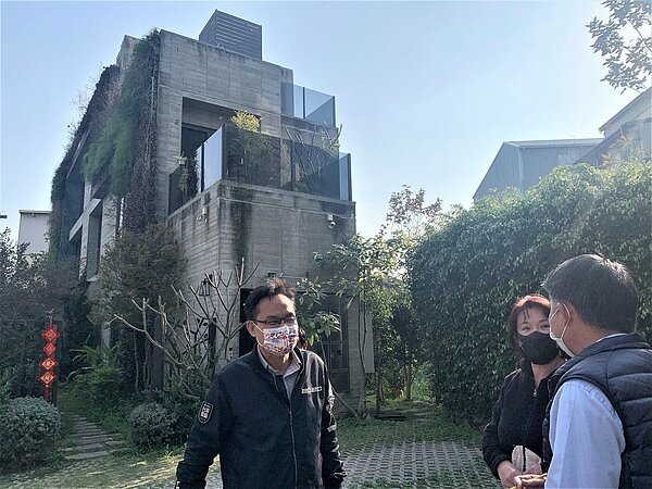 台中市議員張耀中指他身後這處民宅屋頂涉違規裝設基地台。圖/張耀中服務處提供