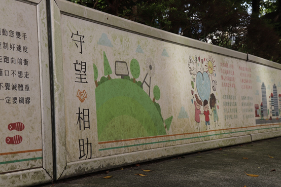 鴻福里玉成公園的圍牆上，印滿由里長劉明康發想的標誌，主要內容與社區和平、居民健康相關。　圖／楊家威攝