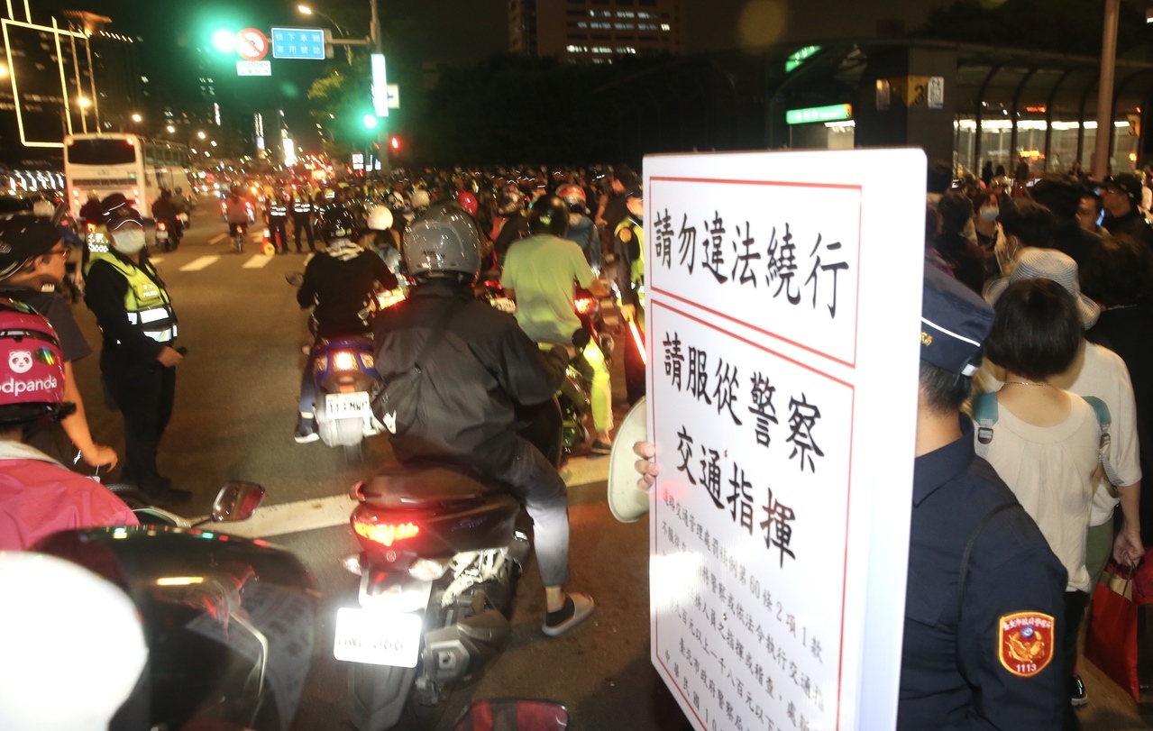 台灣機車路權促進會晚間在台北市市民大道塔城街口舉行「待轉大富翁」訴求取消待轉，現場警方舉牌柔性勸導。記者林俊良／攝影