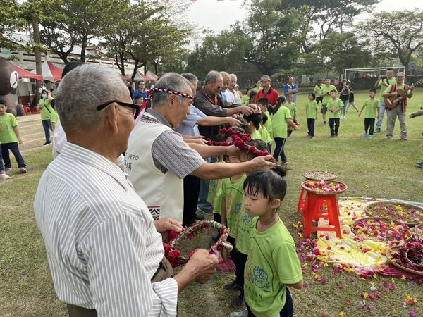 台南新化口埤實驗小學今天慶祝百年校慶，西拉雅長老為小朋友戴上花圈，象徵傳承。圖／校方提供