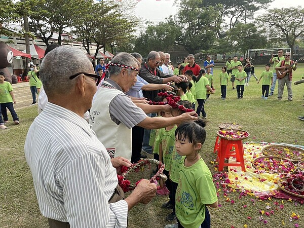 台南新化口埤實驗小學今天慶祝百年校慶,西拉雅長老為小朋友戴上花圈,象徵傳承。圖/校方提供