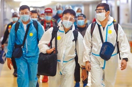 中央流行疫情指揮中心2日宣布,國內新增6例新冠肺炎境外移入案例。在桃園機場入境管制區內,身穿防護衣的旅客正準備通關入境。(范揚光攝)