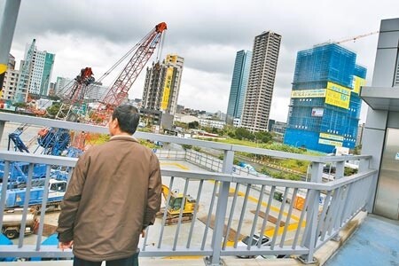 圖為民眾路過新北市新莊區興建中建案，佇足觀看。（杜宜諳攝）