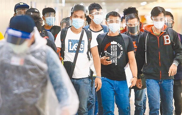 指揮中心連日說法變變變,恐成秋冬防疫的最大罩門。圖為桃園機場入境管制區內,一群剛下機的菲籍移工準備通關入境。(范揚光攝)
