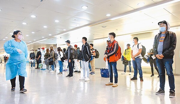 專家呼籲強化防疫旅館的管理措施。圖為桃園機場一群剛下機的菲籍移工,在勞動部人員引導下準備通關。(范揚光攝)