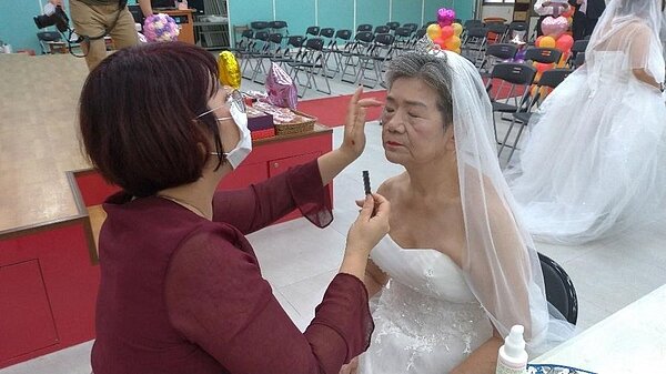 工作人員幫穿著一襲婚紗的長者上妝。里長張永棟提供