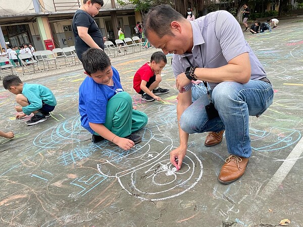 兒童節時，學校舉辦活動，校長朱榮富與學生在校園裡彩繪操場。（校長朱榮富提供）