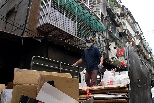 里長在回收車上搬運垃圾，維護里內整潔。圖/江翊柔攝