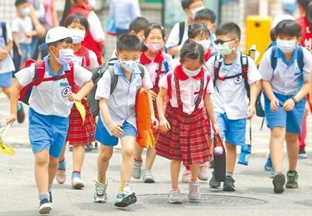 新冠疫情連3天飆新高，確診多數落在台北市與新北市，雙北17日上午宣布，18日起高中職以下停課到28日。圖為小學低年級中午放學，學生們帶著大包小包步出校門回家。（季志翔攝）