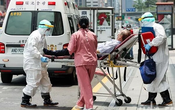 雙北各醫院一床難求,中央啟動「北患南送」機制。圖為台北市救護人員身著全套防護服載送一民眾就醫。記者曾原信/攝影