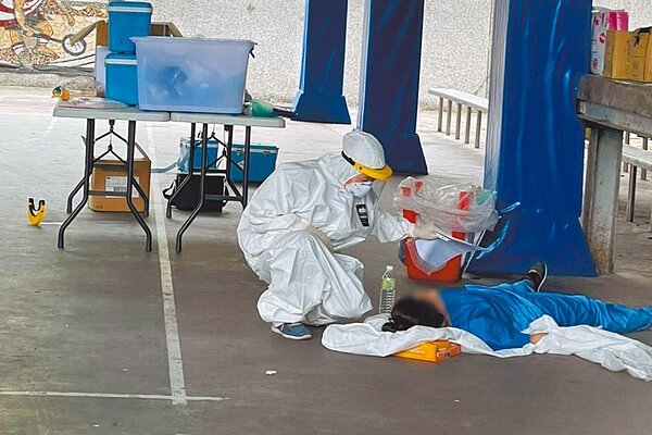 疫情嚴重,醫護備感艱辛,圖為宜蘭羅東1名護理師在大熱天穿防護衣,一度熱痙攣昏倒,同事立即為她補充水分,體力恢復後仍繼續堅守崗位服勤,令人敬佩。(聖母醫院提供)