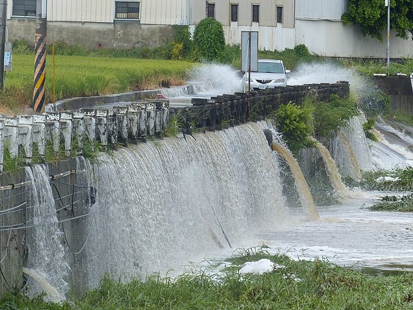 今天清晨的豪雨，從農田洩下彰化市大埔截水溝形成長長的瀑布景觀，車輛越水而過濺起高高水花，十分吸睛。記者劉明岩／攝影 