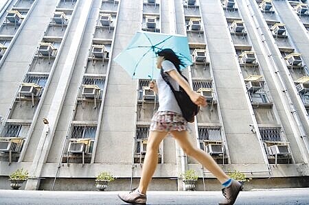 夏月電價6月1日啟動，每月用電量超過120度，就會適用較高的電價。圖為民眾行經掛滿冷氣機的大樓外。（黃世麒攝）