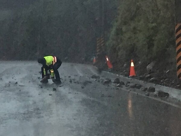 高雄台20線91公里處有落石掉落路面，員警冒雨徒手搬離落石。圖／民眾提供