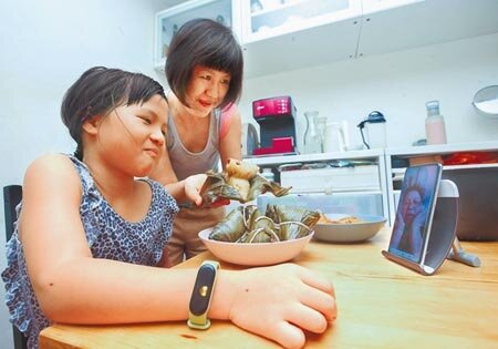 蔡英文總統在臉書提醒,紓困4.0中增加了每位孩童10,000元的孩童家庭防疫補貼,將在6月15日正式上路。圖為端午連假未返鄉民眾,透過手機、視訊軟體與親人同步大啖粽子。(粘耿豪攝)