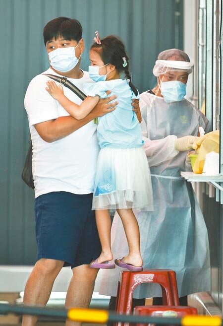 國內新冠肺炎疫情持續延燒,雖適逢端午假期新北市板橋大型篩檢14日仍有許多民眾前往檢測,小朋友檢測完臉頰泛著淚水由父親抱離篩檢處。(陳怡誠攝)