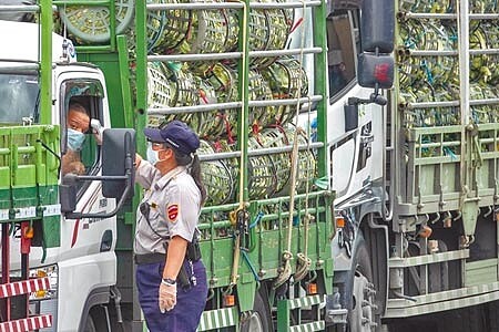 台北農產運銷公司第一果菜市場駐衛警對運菜的卡車司機測量體溫；台北市政府21日前往第一果菜市場會勘快篩站場地，將針對約4000名承銷商展開篩檢及接種疫苗。（黃子明攝）